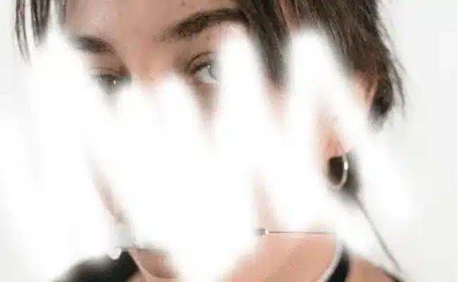 Blurred face with white scribble effect, featuring a person with short hair and hoop earrings. (AI-generated)