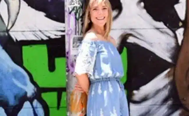 Woman in blue dress posing against vibrant street art mural. (AI-generated)
