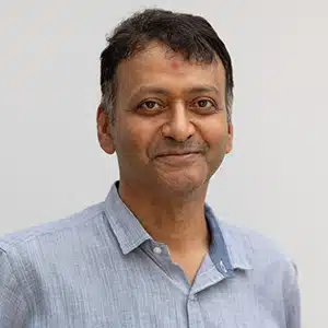 Smiling man in a light blue shirt against a plain background. (AI-generated)