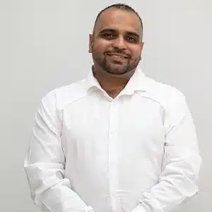 Smiling man in a white shirt against a plain background. (AI-generated)