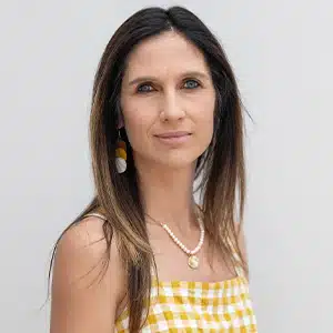 Woman in a yellow checked dress with pendant, neutral background. (AI-generated)