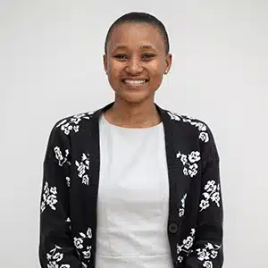 Smiling person in floral cardigan and white shirt against neutral background. (AI-generated)