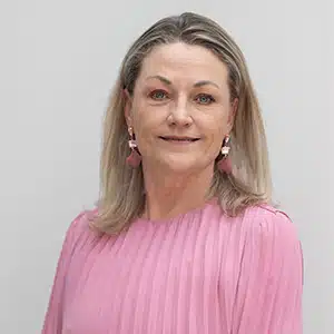 Portrait of a woman in a pink blouse, smiling, with long hair. (AI-generated)