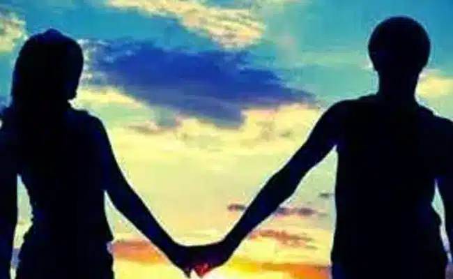 Silhouette of couple holding hands at sunset with vibrant sky. (AI-generated)