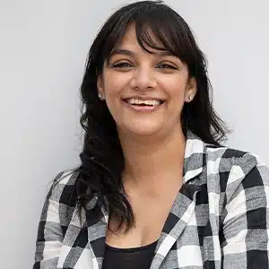 Smiling woman in checkered shirt against a white background. (AI-generated)