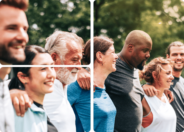 A photo shows a mixed group of smiling people standing arm-in-arm in the sunshine.